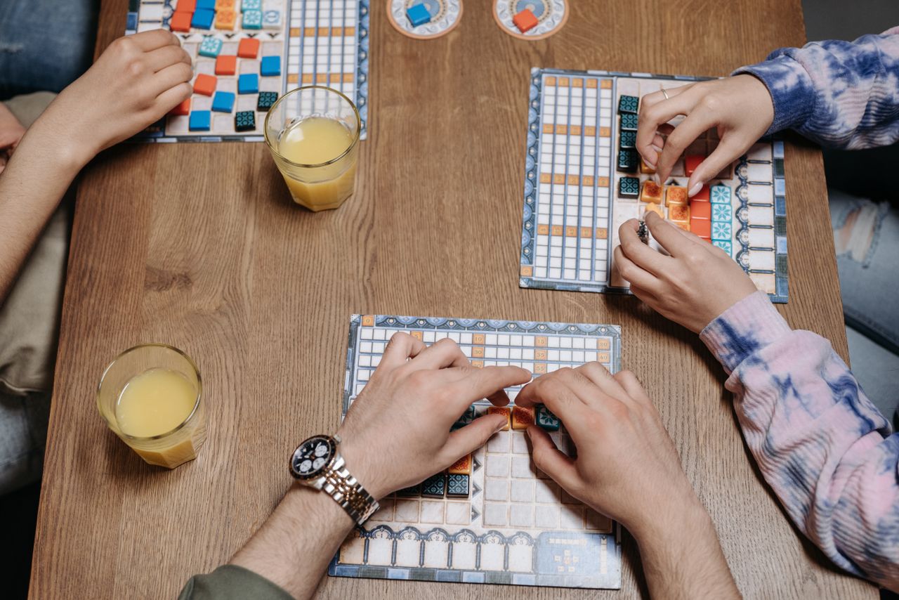 Close-up of hands and board game tiles during a fun gaming session indoors.